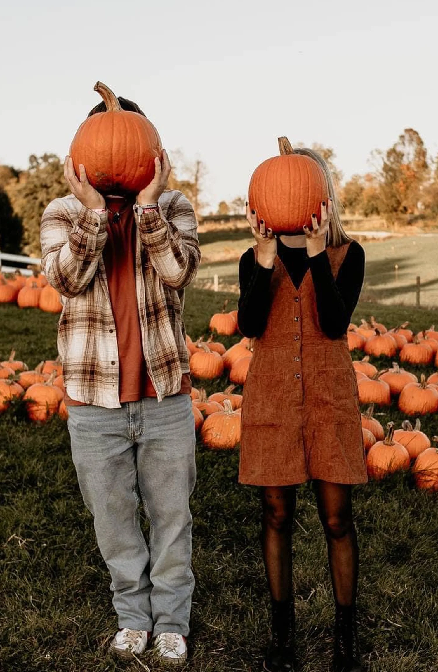 Two kids holding pumpkins up in front of their faces